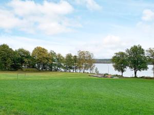a large green field with a view of a lake at 4 person holiday home in HOLSLJUNGA in Holsljunga