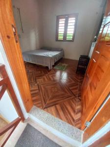 a room with a bed and a wooden floor at CASINHA DA SERRA in Baturité