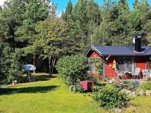 Blidö的住宿－6 person holiday home in BLID，一间红色小屋,在院子里配有桌椅