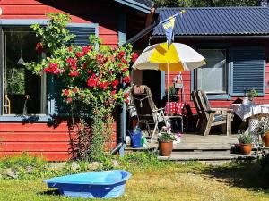 uma casa com um deque, um guarda-chuva e flores em 6 person holiday home in BLID em Blidö
