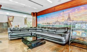 a living room with a leather couch and a painting at Treebo Trend Symphony Hotels And Resorts Angamally in Kizhake Chālakudi