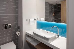 ein Bad mit einem Waschbecken und einem Spiegel in der Unterkunft Holiday Inn Express - Aarburg - Oftringen, an IHG Hotel in Oftringen