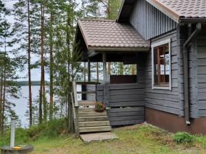 a small house with a porch and stairs next to a lake at Turjanlinna in Rantasalmi