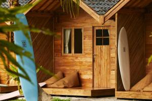 ein Holzhaus mit einem Surfbrett davor in der Unterkunft House of Sawah in Batukaras