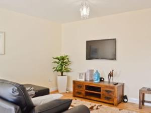 a living room with a couch and a tv on a wall at The Penthouse- The Kingsley Collection in Troon