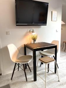 ein schwarzer Tisch mit zwei Stühlen und ein TV an der Wand in der Unterkunft Living at Saarpartments - AdultsOnly - Business & Holiday Homes with Kitchen for Long- and Short Term stay, 3 min to St Johanner Markt and Points of Interest in Saarbrücken