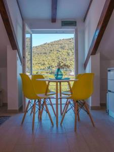 ein Esszimmer mit einem Tisch und gelben Stühlen in der Unterkunft Apartments Filip - vineyard and large terrace in Vis