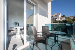 un patio con tavolo e sedie sul balcone. di Apartments Jakov - modern and cosy with pool a Postira (Postire)
