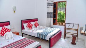 a bedroom with two beds with red and white pillows at The King's Garden Resort in Dambulla
