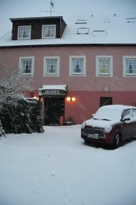 un coche aparcado frente a un edificio en la nieve en Hotel Matheisen, en Colonia