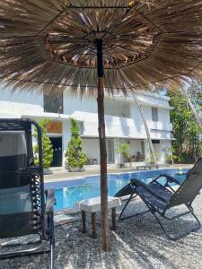 an umbrella and chairs next to a swimming pool at Satta Beach Residence in Varkala