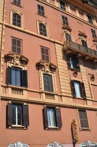 a tall brick building with black shuttered windows at Amico Hotel in Rome