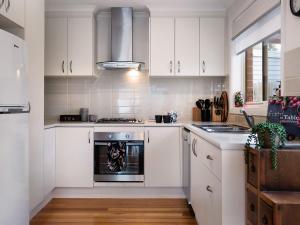 uma cozinha com armários brancos e um forno em Wayfarer Cottage em Daylesford