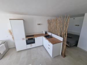 una pequeña cocina con armarios blancos y encimera en Superbe Studio Rénové les pieds dans l'eau! en Marseillan