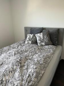ein Bett mit einer grauen und weißen Bettdecke und Kissen in der Unterkunft Gemütliche Villa am Waldrand in Taunusstein in Taunusstein