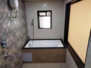 a bathroom with a bath tub and a window at Sun Inn Residency in Mumbai