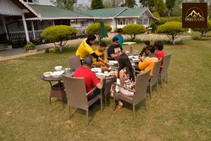 een groep mensen die rond een tafel eten bij Tumsong Tea Retreat in Darjeeling