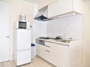 a white kitchen with a microwave and a refrigerator at Fuchsia - Vacation STAY 29048v in Nagoya