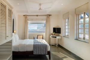 a bedroom with a bed and a desk and a window at O Pierre in Panaji