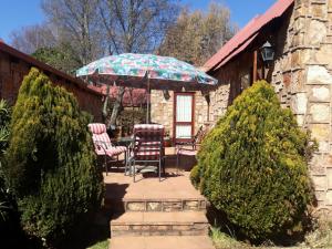 a patio with two chairs and a table with an umbrella at Marigold's 37 Critchley Common in Dullstroom
