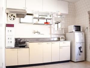 a kitchen with white cabinets and a white refrigerator at Calm house Beppumotomachi in Beppu