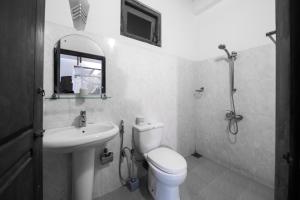 Baño blanco con aseo y lavamanos en Prime Time Hotel, en Unawatuna