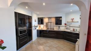 a large kitchen with black cabinets and appliances at Geräumiges und Modernes Apartment Tara am Meer mit Parkplatz! in Zandvoort