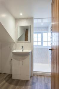 a white bathroom with a sink and a window at Stunning 4 Bedroom Cottage-Sleeps 8-Free Parking in Gloucester