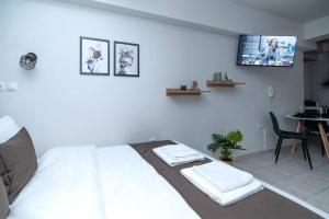 Schlafzimmer mit einem weißen Bett und einem TV an der Wand in der Unterkunft Larissa city center appartment ολοκαίνουργιο κομψό in Larisa