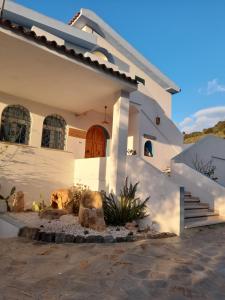 a white house with a staircase in front of it at Agriturismo Palas De Serra Country Resort in Onifai
