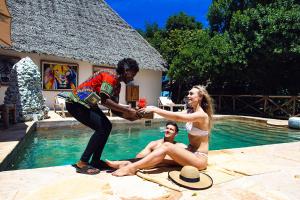 a man and a woman are sitting in a swimming pool at The Island - Pongwe Lodge in Pongwe