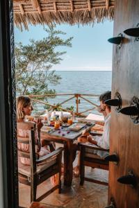 um casal sentado numa mesa na praia em The Island - Pongwe Lodge em Pongwe