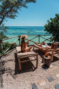 dwie osoby siedzą na ławkach na plaży w obiekcie The Island - Pongwe Lodge w mieście Pongwe