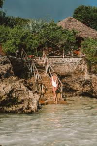a woman standing on steps in the water at The Island - Pongwe Lodge in Pongwe