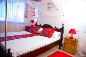 una camera con letto a baldacchino e cuscini rossi di Lux Suites Royal Family Apartment Nyali a Mombasa
