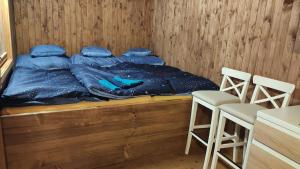 a bed with blue pillows and two chairs in a room at Maringotka/tiny house SEN VYSOČINA in Věstoňovice