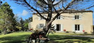 una casa con un árbol delante de ella en Chambres d'hôtes - Le Moussat, en Lagraulet-du-Gers