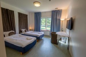 Cette chambre comprend 2 lits et une fenêtre. dans l'établissement Systemairhallen Bed&Breakfast, à Skinnskatteberg
