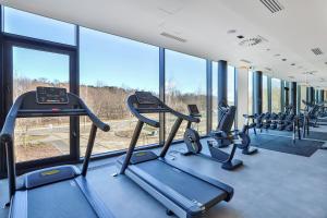 a gym with treadmills and elliptical machines and windows at Luxury Tarasy Bałtyku with Stunning Views & Sauna & Gym by Renters Prestige in Gdańsk
