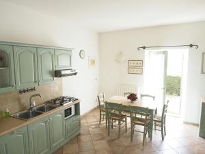 eine Küche mit grünen Schränken und einem Tisch mit Stühlen in der Unterkunft Appartamenti I Cortivi in Costermano sul Garda