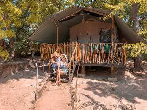 duas mulheres sentadas num banco em frente a uma tenda em Camp Leopard - Yala Safari Glamping em Yala