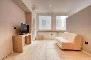 Apartment Passarella 4 في ميلانو: غرفة معيشة بها أريكة بيضاء وتلفزيون