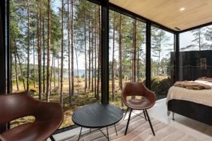 a bedroom with a bed and chairs in front of a window at Santalahti Resort Cottages & Villas in Kotka
