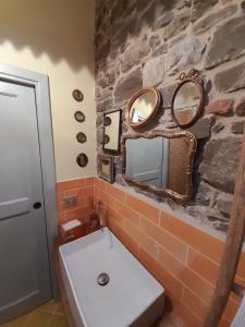 a bathroom with a stone wall with a sink and mirrors at Guelfi6 Poppi in Poppi