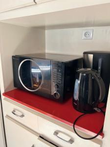 a microwave sitting on a red counter in a kitchen at L’ÉMERAUDE 4 in Chalons en Champagne