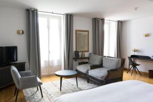 a room with a bed and a couch and a tv at Hotel Beau Site - Rocamadour in Rocamadour