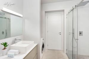 La salle de bains blanche est pourvue d'un lavabo et d'une douche. dans l'établissement Deluxe Loft 2BR in White City by HolyGuest, à Tel Aviv