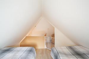 2 bedden in een zolderslaapkamer met een trap bij Hello Zeeland - Vakantiehuis Beatrixstraat 27A in Domburg