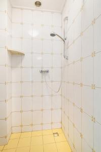 a bathroom with a shower and a yellow tile floor at Hello Zeeland - Appartement Beatrixstraat 27 in Domburg