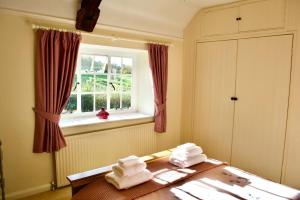 ein Schlafzimmer mit Handtüchern auf einem Tisch und einem Fenster in der Unterkunft Charming Cottage, Great Rissington, Cotswolds in Great Rissington
